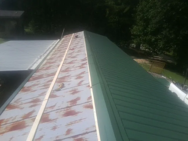Old rusted panels beside newly installed green metal roofing — Wind Damage Roof Repair by Roofing Brothers in Round Lake