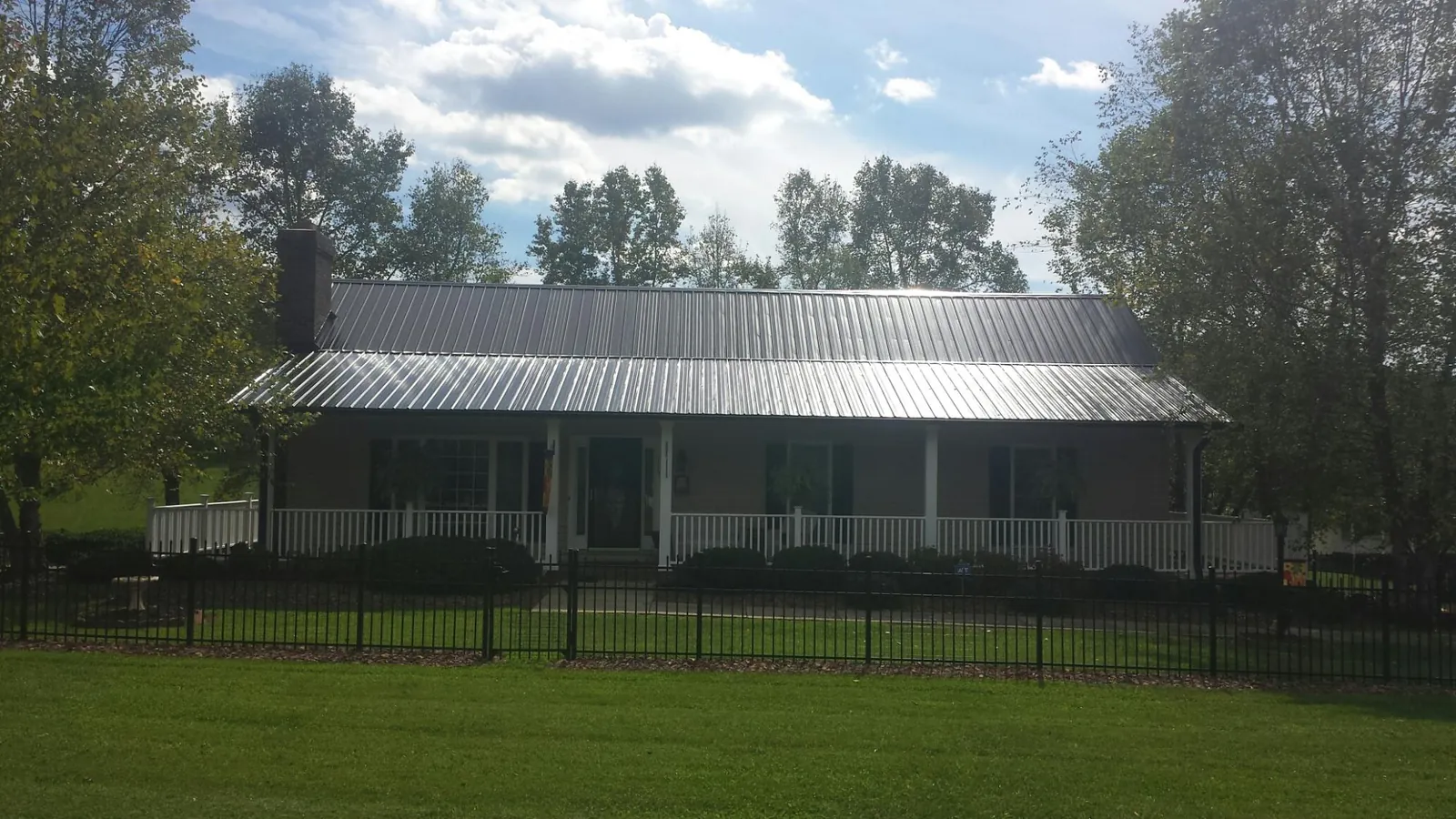 Gray metal roof on a brick ranch with a full width front porch — Gutter Guard Installation work by our crew in Round Lake
