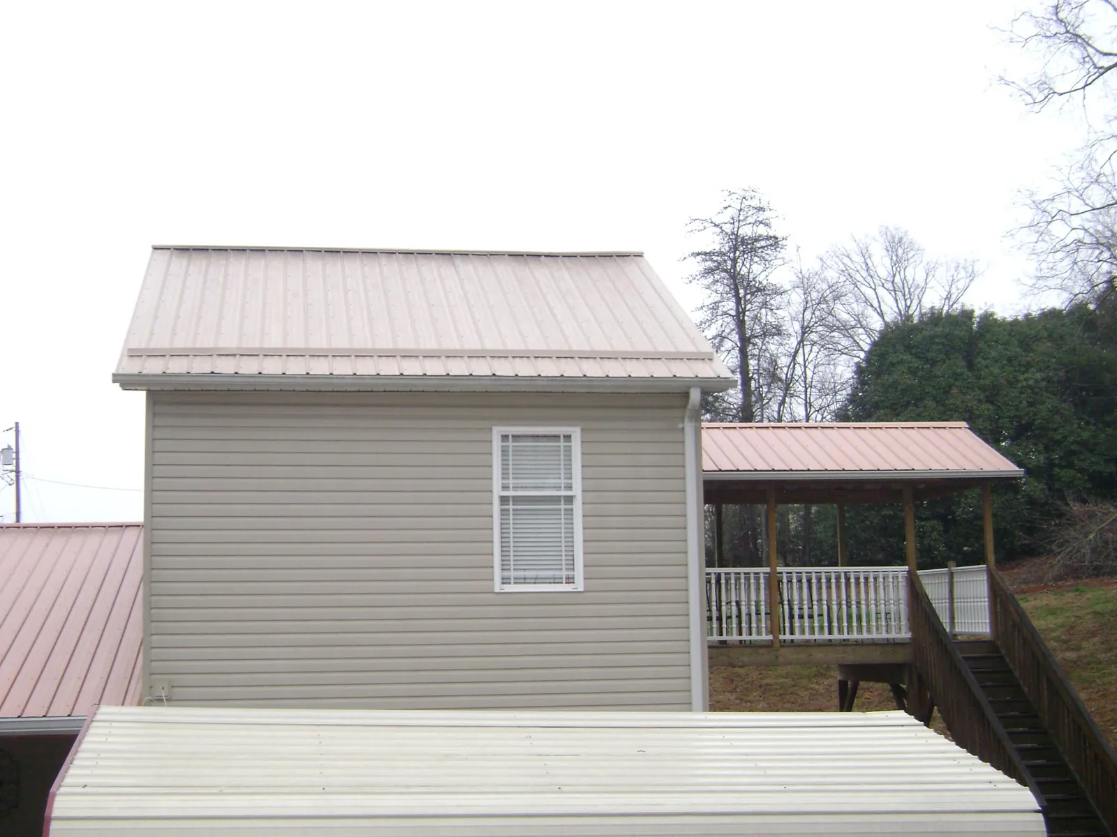Tan metal roofs on a two story addition and attached porch, from a Roof Replacement job in Round Lake